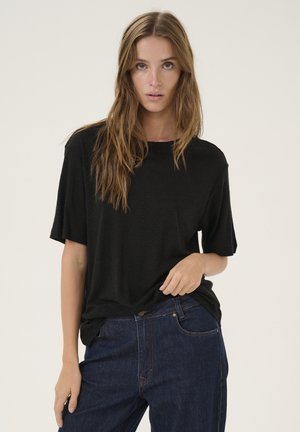 Black, loose-fitting short-sleeve t-shirt made of soft fabric, paired with dark denim jeans featuring front pockets and subtle stitching.