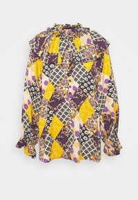 Blouse à manches longues avec un col froncé, fabriquée en tissu à motifs avec des designs jaunes, violets, noirs et floraux dans diverses textures.