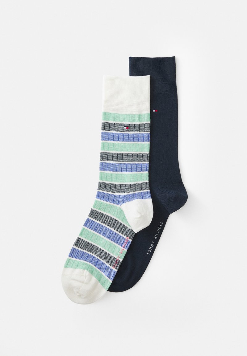 Striped socks featuring a multicolored pattern of green, blue, and gray on one sock, and solid dark navy on the other; made of cotton.