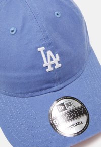Helle blaue Baumwollmütze mit weißem, gesticktem "LA"-Logo. Mit verstellbarem Riemen und einem runden New Era-Branding-Aufkleber.