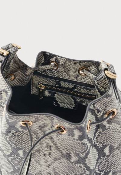 Offene Bucket-Tasche mit Schlangenledermuster, goldenen Ösen, Kordelzugverschluss und innerer Reißverschlusstasche vor einem einfarbigen Hintergrund.