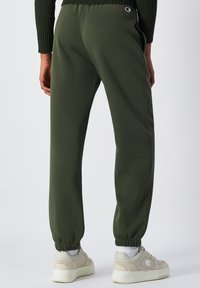 Pantaloni da tuta verde oliva con polsini elastici, tasche laterali e logo Champion sul retro; realizzati in tessuto morbido e leggero.