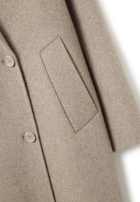 Beige wollen jas met twee bijpassende knopen en een rechthoekige klepzak aan de voorkant, met zicht op mouw- en zijdetails.