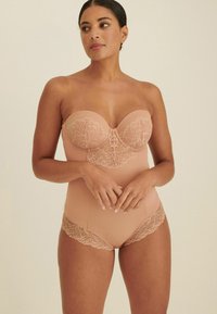 Strapless bodysuit in lichtbeige, met een bloemenkantdetail op het lijfje en kantafwerking langs de beenopeningen, gladde textuur.