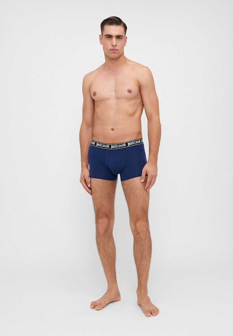 Boxeri bleu marin cu un design solid, având o talie neagră inscriptionată "justcavalli." Materialul pare a fi neted și elastic.