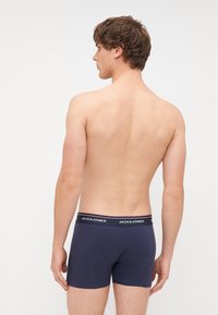 Tamno plave pamučne bokserice s kontrastnim crnim pojasom na kojem je brend "JACK & JONES"; pogled sa stražnje strane, glatka tekstura i prilagođen dizajn.
