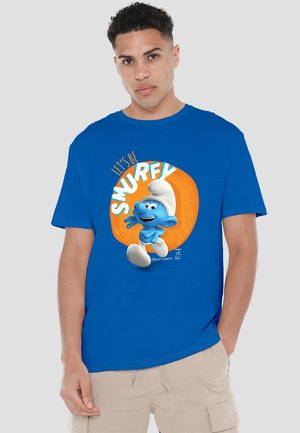 Blaues Baumwoll-T-Shirt mit einem blauen Cartoon-Charakter mit einem weißen Hut, orangefarbigem, kreisförmigem Hintergrund und dem Text "LASST UNS SMURFEN" darüber.