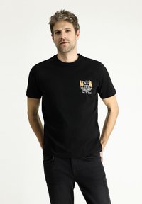 Camiseta de algodón negra con cuello redondo, que presenta un gráfico naranja de una autocaravana vintage y árboles con el texto "Es hora de viajar".