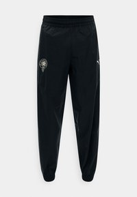 Μαύροι φόρμες Puma με ελαστική μέση και μανσέτες, με λευκό λογότυπο Puma στο δεξί μηρό και στρογγυλό έμβλημα στο αριστερό μηρό.