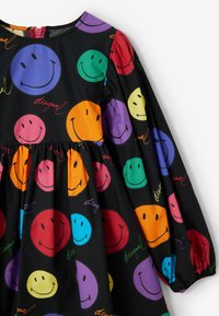 Czarna sukienka z długimi rękawami, ozdobiona kolorowymi wzorami uśmiechniętych buziek w odcieniach pomarańczowym, purpurowym, zielonym, niebieskim i różowym na gładkiej tkaninie.