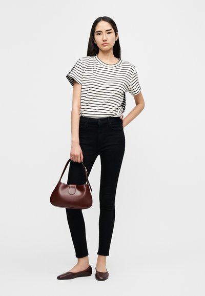Ριγέ κοντομάνικη μπλούζα, μαύρο στενό τζιν, καφέ δερμάτινη τσάντα με στρογγυλεμένο σχήμα και καφέ επίπεδα παπούτσια. Απλό, καθημερινό ντύσιμο.