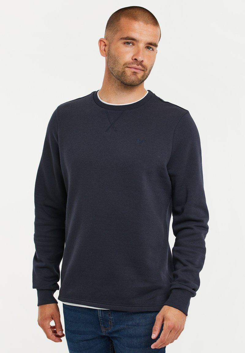 Navyblauwe sweatshirt met lange mouwen, ronde hals en geribde manchetten. Bevat een subtiele logo op de borst. Zachte stoftextuur.