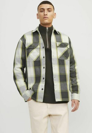 Plaid flannel shirt in grey, white, and lime green, with a button-up front, chest pockets, and a layered dark green sweater underneath.