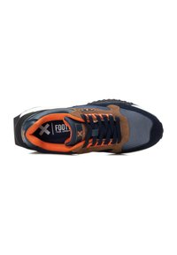 Las zapatillas presentan una parte superior de malla azul marino y ante marrón, acentos naranjas, suela de goma negra y cierre de cordones negro con detalle del logo en la lengüeta.