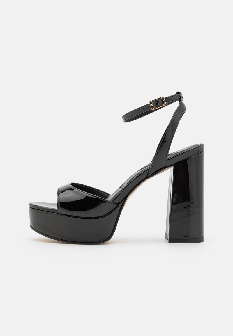 Sandales à plateforme en cuir verni noir avec une sangle pour la cheville, présentant un talon haut épais et un design à bout ouvert. Texture lisse et finition brillante.