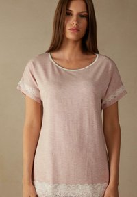 Lichtroze T-shirt met korte mouwen, een ronde hals en witte kantdetails op de mouwen en de zoom. Zacht, gestructureerd materiaal.