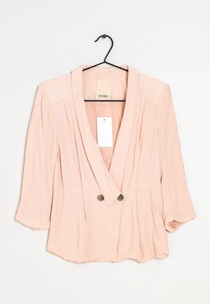 Vaaleanpunainen, kevyt takki, jossa on kietaisumalli, napitus, pitkät hihat ja kaksi etunappia. Takki on pehmeää materiaalia ja minimalistisella designilla.