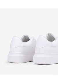 Sneakers bianchi a basse silhouette realizzati in pelle liscia. Presentano una punta arrotondata, un colletto imbottito e una suola in gomma piana. Accenti di cucitura sottili.