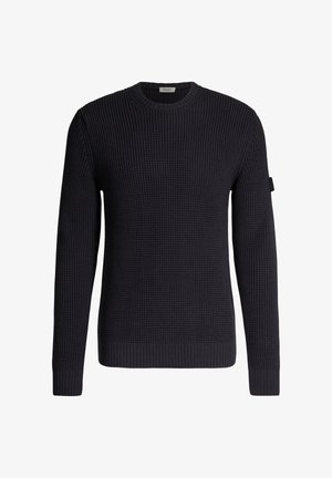 Maglione nero a coste con maniche lunghe e scollo rotondo, polsini e orlo a coste, con una piccola etichetta in tessuto sul braccio superiore.