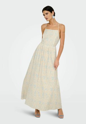Ärmelloses Maxikleid in zartem Gelb mit blauem Blumenmuster, taillierter Oberteil, elastischer Taille und fließendem Rock; kombiniert mit blauen High Heels.