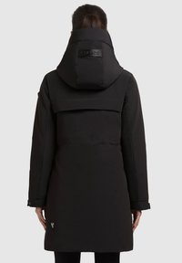 Sort parka med høj krave, hætte og en mat finish. Har en flap bagpå og logo detaljer på hætten. Længde ærmer og tryklåse ved manchetterne.