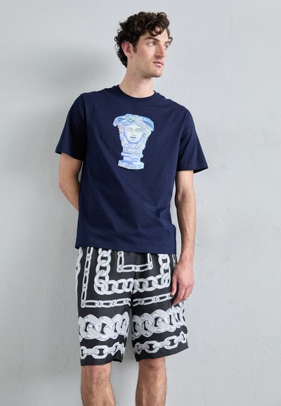 Navy cotton t-shirt featuring a colorful bust graphic. Paired with black shorts displaying a white chain pattern.