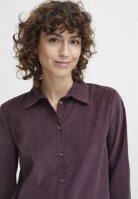 Dark purple corduroy shirt with collar, button front, and long sleeves. Features subtle texture and round brown buttons.