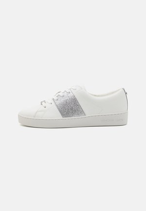 Baltas ādas sporta apavi ar mirdzošu sudraba svītru, teksturētu virsmu, apaļu purngalu, kurām ir šņorēšanas aizdare un viegla zole ar zīmola detalizāciju.