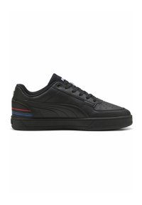 Adidași din piele neagră cu vârf perforat, șireturi plate negre și sole din cauciuc. Prezintă o dunga roșie și albastră pe călcâi.