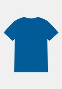 Camiseta de algodón azul con diseño de cuello en V, mangas cortas y detalles de costura mínimos, con un acento en rojo y blanco en el cuello.