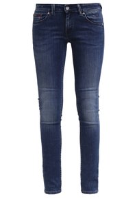 Jeans ajustados en denim azul oscuro, con un diseño clásico de cinco bolsillos, un desgaste sutil y un cierre de botón con un detalle de remache metálico.