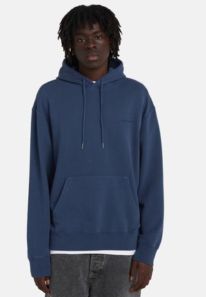 Granatowa bluza z kapturem z przednią kieszenią, sznurkami i ściągaczami przy mankietach. Na piersi dyskretne logo. Wykonana z miękkiej bawełnianej mieszanki.