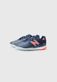 Zapatillas deportivas azul marino con parte superior de cuero texturizado, detalles en rojo, lengüeta acolchada y suela translúcida con tacos de goma.