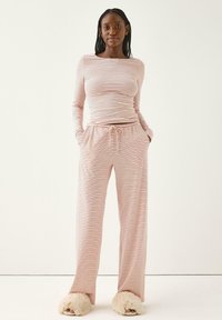 Langærmet stribet top og brede pyjamasbukser i blødt stof, med elastisk talje og snoretræk. Akkareret med fluffy slippers.