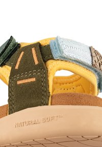 Sandaler med en blandning av gul tyg och gröna, blå och beiga lappar; mjuka, texturerade remmar; och en beige gummisula med "NATURAL SOFT" varumärke.