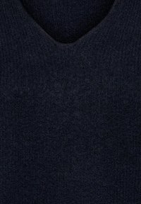 Gros plan d'un tissu texturé bleu marine foncé avec un col rond, montrant une surface douce et duveteuse.