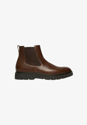 Stivale Chelsea in pelle marrone con pannelli laterali elastici, punta rotonda e suola in gomma nera con texture. Dettagli cuciti lungo la base.