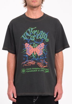 Camiseta de algodón negra con un diseño colorido de mariposa, manos y texto en verde y naranja. Mangas cortas y corte relajado.