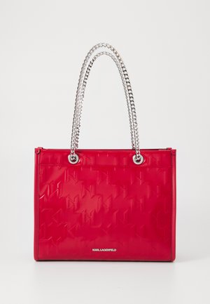 Punane läikiv käekott, millel on reljeefne geomeetriline muster, hõbedased ketist käepidemed, lukuga sulgemine ja Karl Lagerfeldi logo esiküljel.