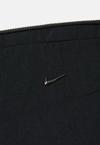 Acessório preto de tecido Nike com uma textura suave, design elegante e um detalhe de logotipo metálico. Parte superior com fecho zip e bordas costuradas.