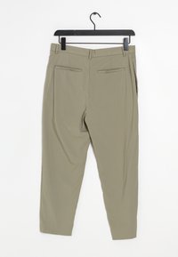 Pantaloni color khaki appesi a un gancio, con una texture liscia, gambe affusolate, due tasche posteriori e un davanti piatto senza chiusure visibili.