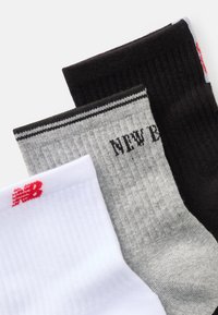 Trojica párov ponožiek v bielej, šedej s čiernymi akcentmi a čiernej farbe. Obsahuje rebrový textúru a logo New Balance v červenej farbe.