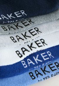 Chaussettes empilées en tissu tricoté bleu marine, gris, blanc et bleu, avec le mot « BAKER » visible en tricot dans des couleurs contrastées.