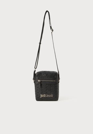 Mala tiracolo preta feita de material estampado, apresentando um bolso frontal com fecho de correr, alça ajustável e detalhe de logotipo metálico.