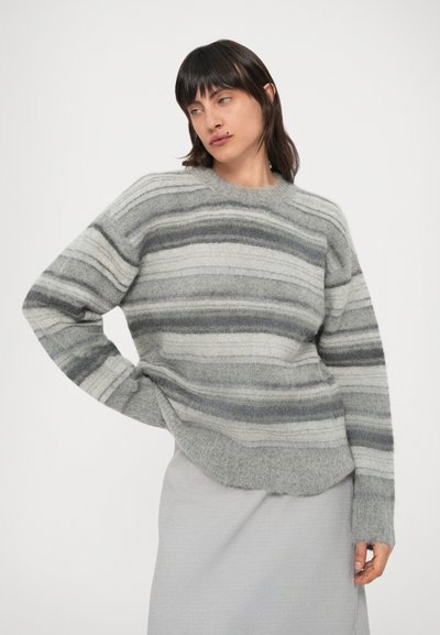 Hall triibuline kampsun, valmistatud pehmest, karvasest kangast. Omaduseks horisontaalsed triibud hele- ja tumedashallides toonides. Ümar kaelus ja langetatud õlad.