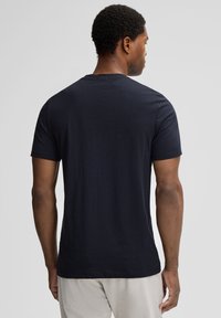 T-shirt en coton bleu marine avec un col rond classique et des manches courtes, avec un design simple et une texture lisse.