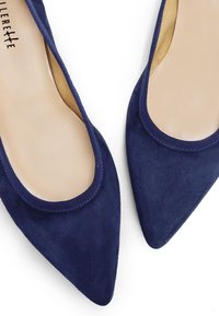 Ballerine in suede blu navy con punta affusolata, apertura elasticizzata e rivestimento beige morbido. Il materiale ha una consistenza soffice senza motivi visibili.