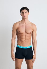 Schwarze Boxerbriefs mit einem hellblauen Nike-Logo am Bund, körperbetonter Schnitt, aus Baumwolle und in mittlerer Oberschenkel-Länge.