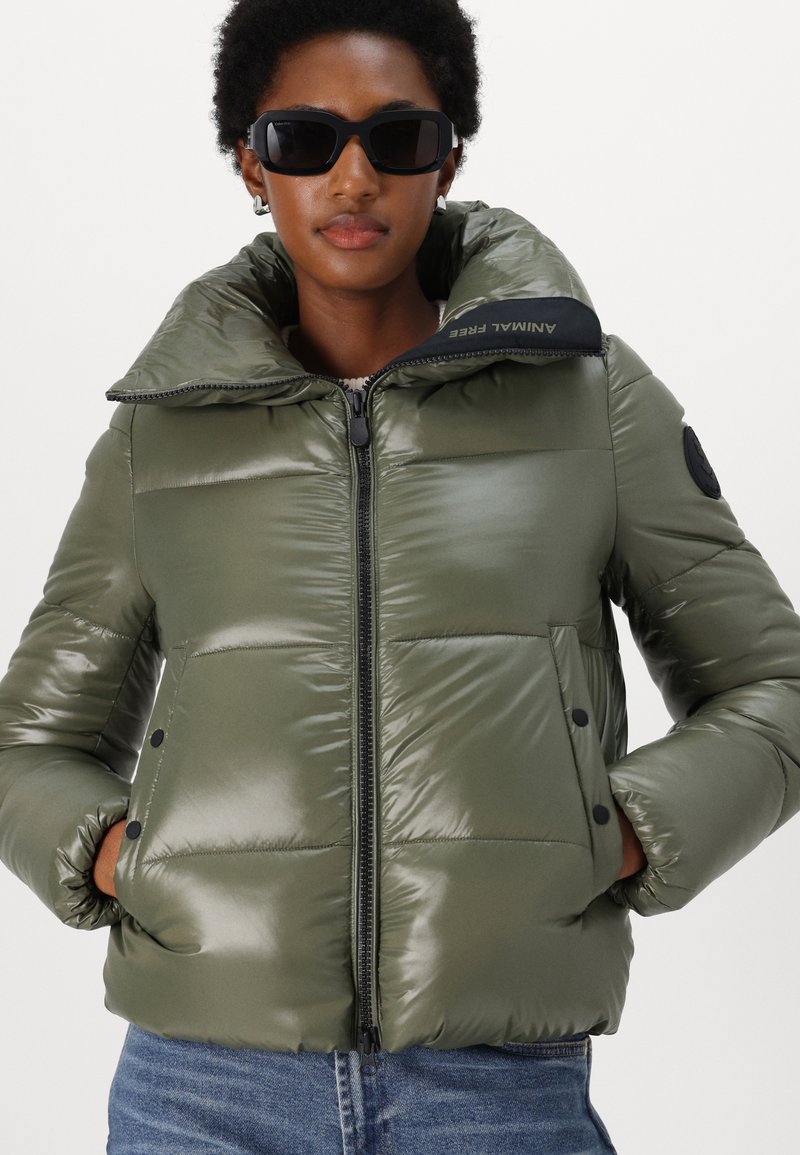 Dunkelgrüne, gepolsterte Jacke mit glänzender Oberfläche, übergroßer Kragen, Frontreißverschluss, zwei knöpfbare Taschen und einem schwarzen Logo-Detail am Kragen.