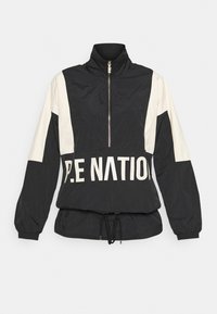 Svart och krämfärgad vindjacka med hög krage, halvdragkedja, elastiska ärmmuddar, dragsko i nederkant och "P.E NATION" tryckt i fet stil.